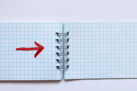 Red arrow drawn with a brush on a spread of a notebook in a squared spiral as 스톡 사진