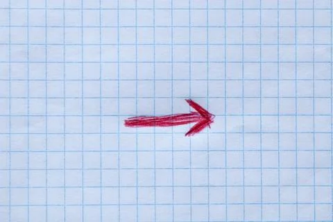 A red arrow drawn by hand on a sheet of squared notebook that points to the.. Stock Photos