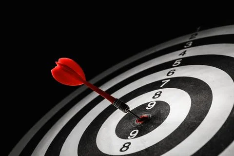 Red arrow hitting target on dart board against black background Foto stock