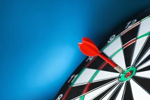 Red arrow hitting target on dart board against blue background. Space for tex Stock Photos