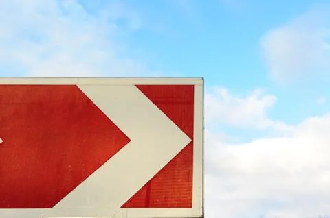 Red arrow pointer on sky background. Roadside with and cloudy sky. Road turn Foto stock