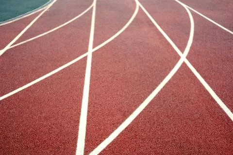 Red athletic track surface with white lane markings, showcasing the curved lines Stock Photos