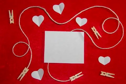 A red background from felt. A composition from heart, thread and clothespins. Stock Photos