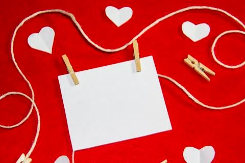 A red background from felt. A composition from heart, thread and clothespins. Stock Photos