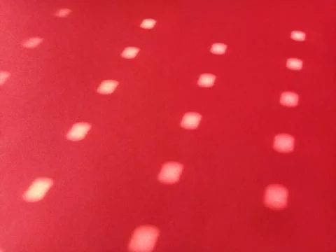 Red background with polka dots. Rays of the sun shining through the holes in  Stock Photos