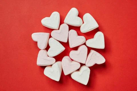 On a red background white and light pink marshmallows in the form of a heart Stock Photos