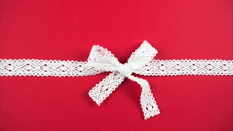 Red background with white lace bow. Ribbon weave Video stock 145312867