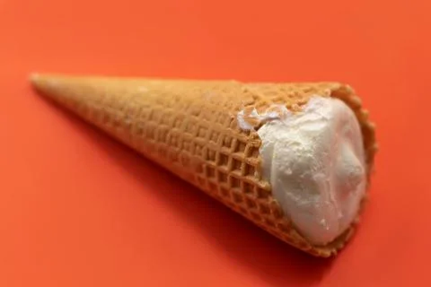 On a red background is a whole waffle cone with ice cream Stock Photos