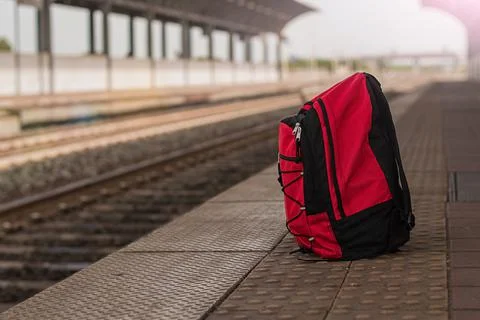 Red backpack against the background of a deserted railway station Stock Photos