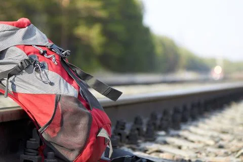 Red backpack at the railway in the pine forest. Travel concept Stock Photos