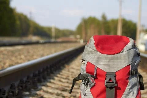 Red backpack at the railway in the pine forest. Travel concept Stock Photos