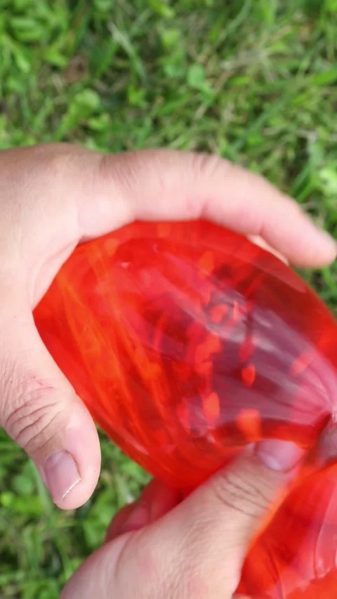 Red balloon squeezed and stretched on grass Stock Footage 318524609