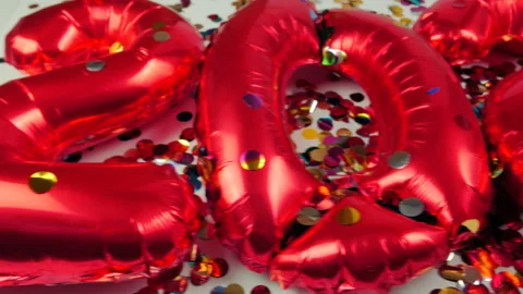 Red balloons in the form of numbers on a white background, falling confetti Stock Footage 144690549