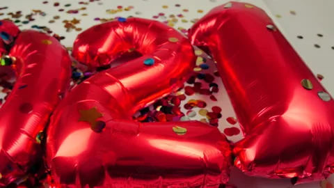 Red balloons in the form of numbers on a white background, falling confetti Stock Footage 144690742