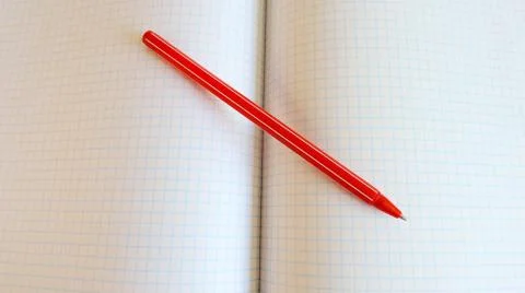 Red ballpoint pen on a sheet of squared notebook closeup with space for text Stock Photos