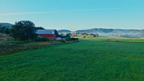 Red Barn House In Green Fields With Rolling Hills At Foggy Sunrise. Aerial Stock Footage 331374120