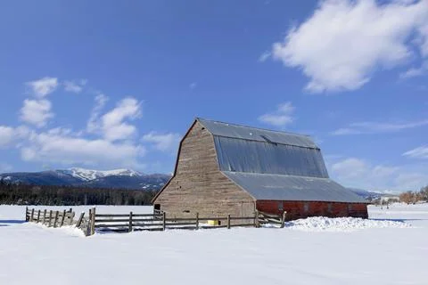 Red barn under a blue sky in winter. Stock Photos