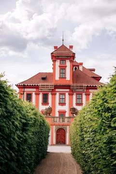 Red baroque palace viewed through green hedge corridor. Historic architecture Fotos Stock