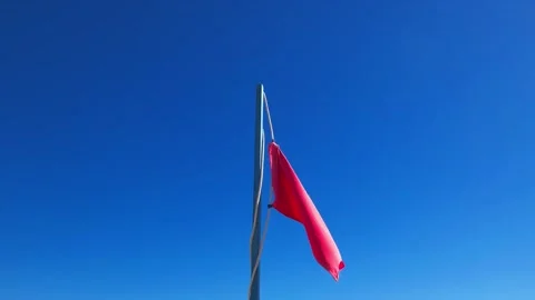 Red beach flag fluttering in the wind, close-up Stock Footage 332490840