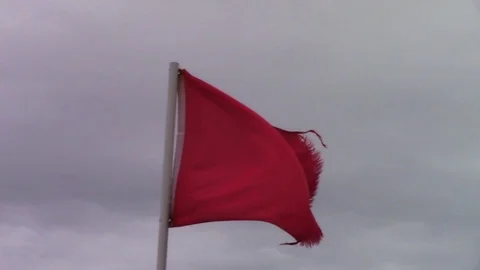 Red Beach Hazard Flag Blowing in Wind with Overcast Sky Stock Footage 105546805