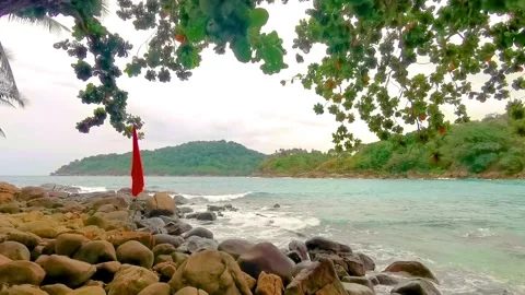 Red beach warning flag among rocks under monsoon clouds Karon Phuket Thailand Stock-Footage 346136824