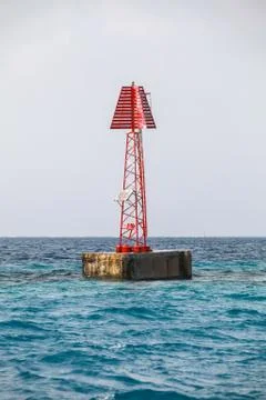 Red beacon with triangle top mark stands in water Stock Photos
