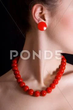 Red beads and a round shackle around his neck a beautiful girl Stock Photos