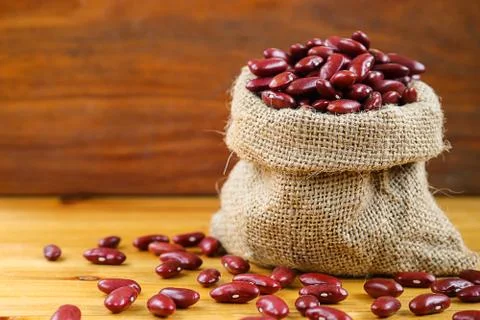 Red bean or red kidney bean in hemp sack on wooden background. Stock Photos