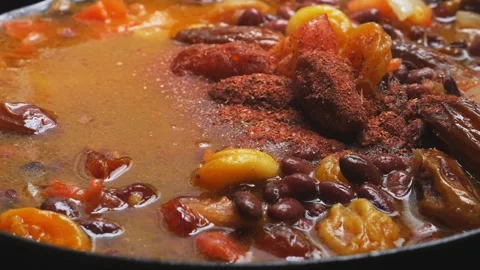 Red beans are stewed in tomato sauce with dried fruits, spices are sprinkled Stock Footage 303850656