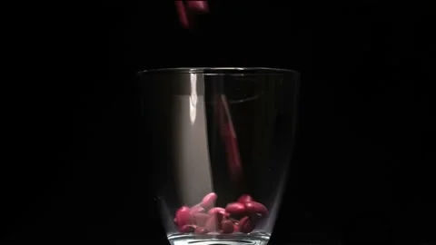 Red beans fall into a glass on a black background Video stock 197025673
