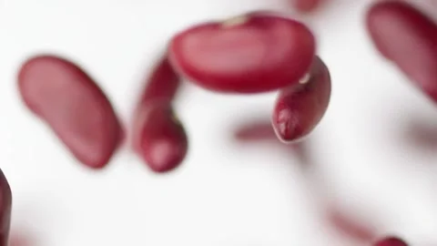 Red beans flies in slow motion on the white background close up Video stock 148553867