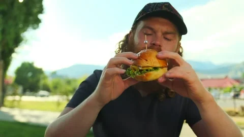 Red bearded caucasian man eats meat burger Stock Footage 279434997