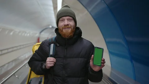 A red-bearded courier with a mobile phone with a chromakey. Food delivery Stock Footage 236089012