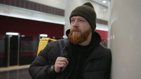 Red-bearded courier with a yellow backpack standing on the subway platform Stock Footage 236089552