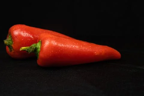 Red bell pepper on a black background. Black fabric background in folds. Stock Photos