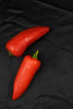Red bell pepper on a black background. Black fabric background in folds. Stock Photos