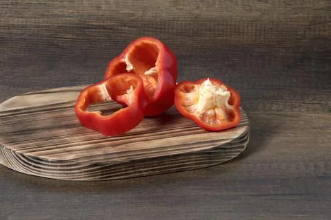 Red bell pepper cut into three pieces on a cutting board. Stock Photos