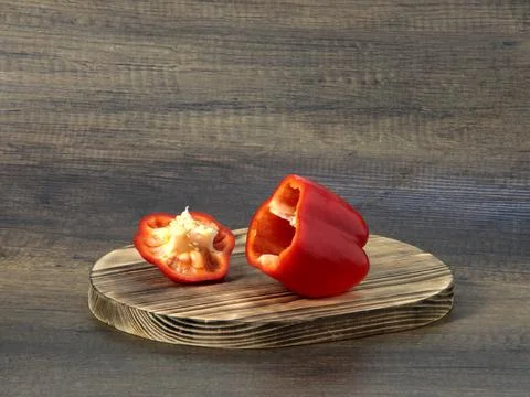 Red bell pepper cut in two on a cutting board. Stock Photos