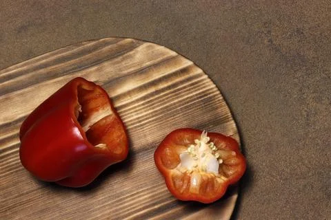 Red bell pepper cut in two on a cutting board. Stock Photos