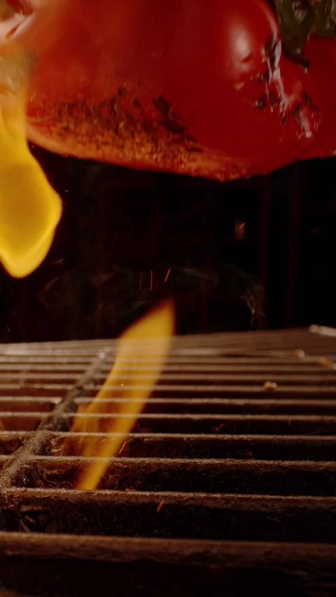 Red bell pepper falling onto a hot metal grill rack with open flames in a s.. Stock Footage 337524481