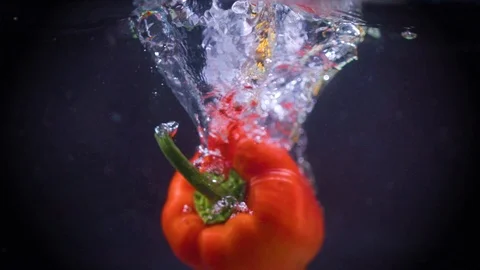 Red bell pepper falls into water. Slow motion. Black background. Food video Video stock 122979645
