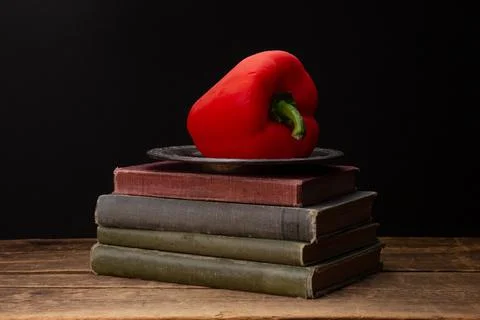 Red Bell Pepper on a plate on a stack of books Stock Photos