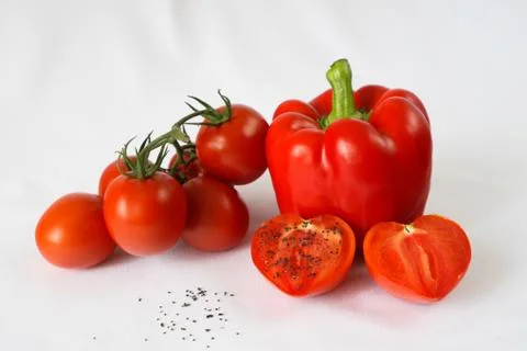 Red bell pepper, red cherry tomatoes, black salt, white background Stock Photos