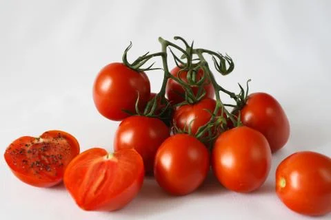 Red bell pepper, red cherry tomatoes, black salt, white background Stock Photos
