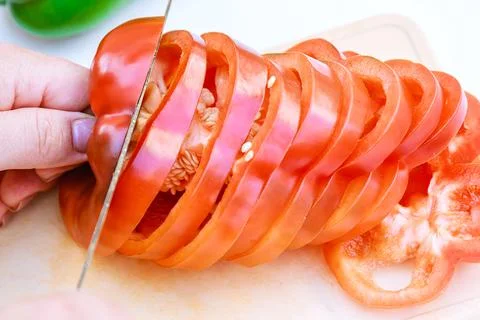 Red bell pepper sliced in thin slices on a white background. Foto stock