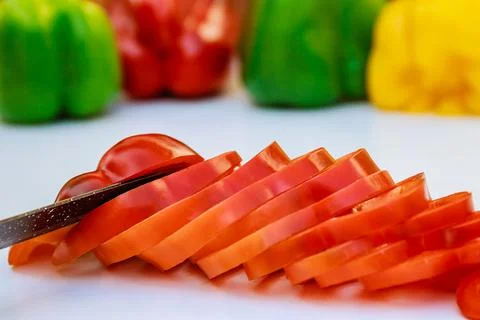 Red bell pepper sliced in thin slices on a white background. Stock Photos