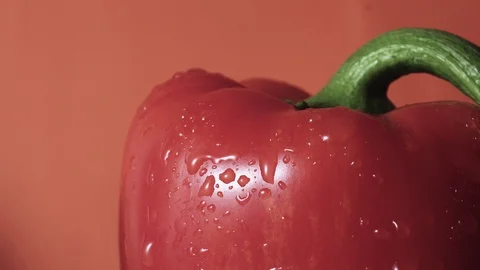 Red bell pepper spray close up, drops of water going down, orange background Stock Footage 102569245
