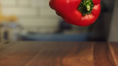 Red bell peppers falling on a table in slow motion Stock Footage 152904874