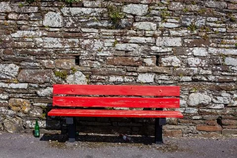 Red bench in front of stone wall with beer bottles Stock Photos