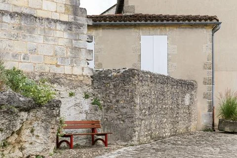 A red bench is sitting on a stone wall in Cognac France Stock Photos